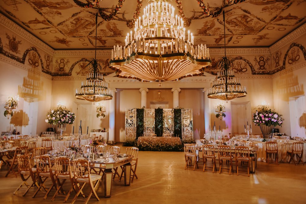 A banquet hall set for dinner under chandeliers
